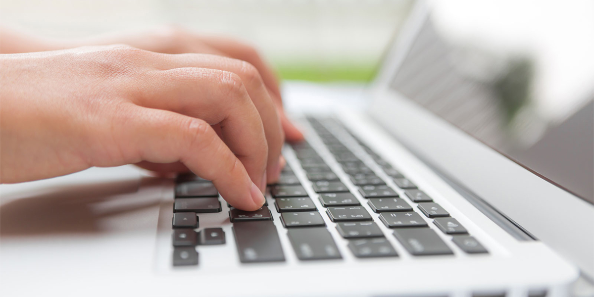 Fingers typing on laptop keyboard.