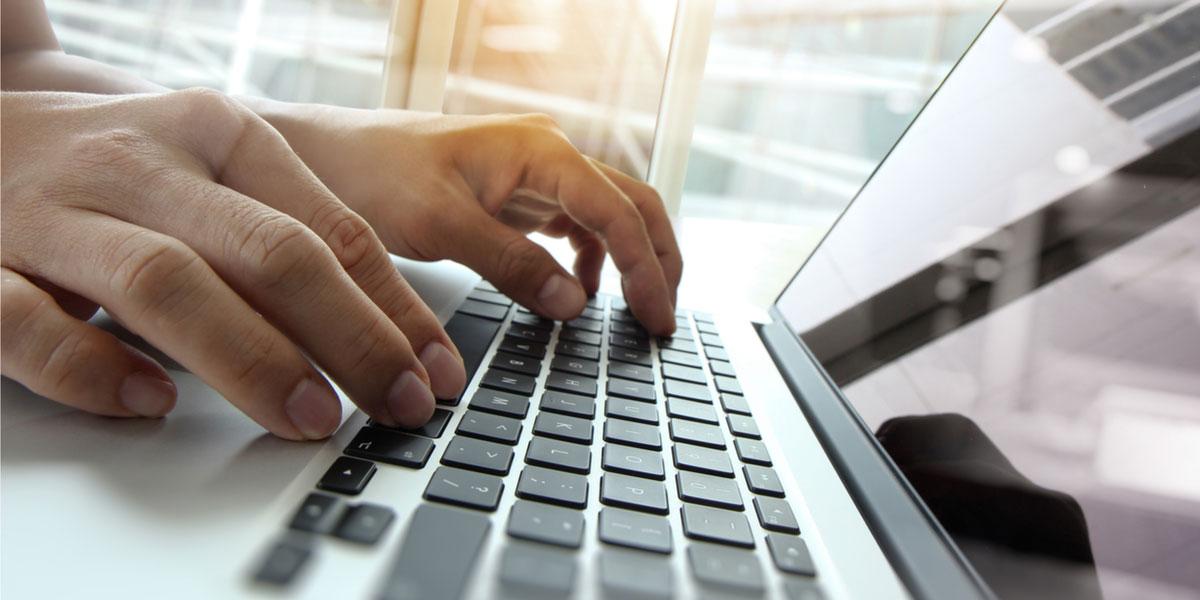 Hands typing on laptop keyboard.