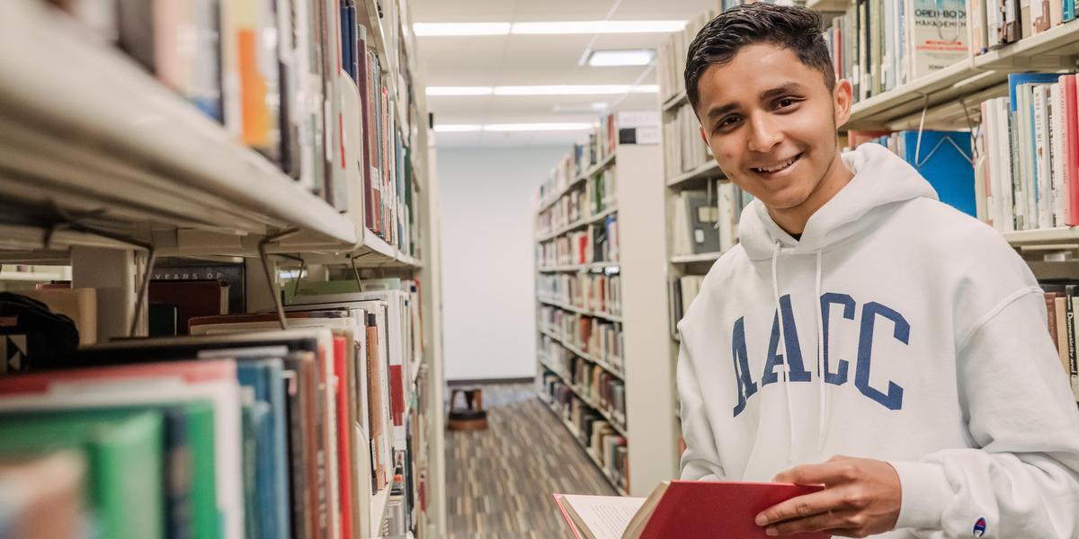 Student smiling for camera with book inside the Truxal Library