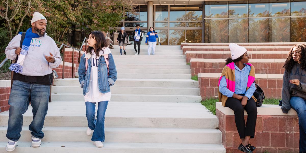 Group of students talking to one another outside in amphitheater.